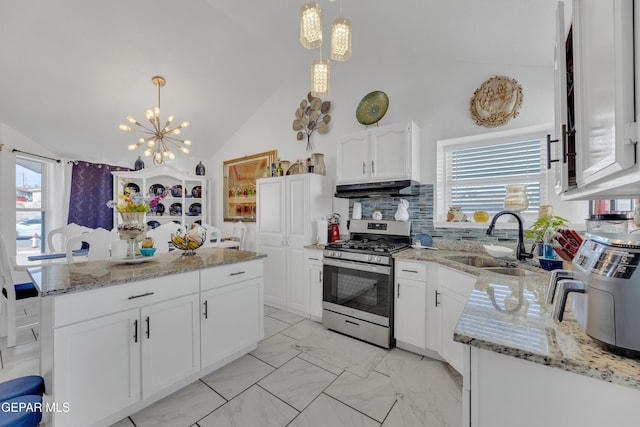 kitchen with under cabinet range hood, stainless steel gas range oven, vaulted ceiling, a sink, and a center island