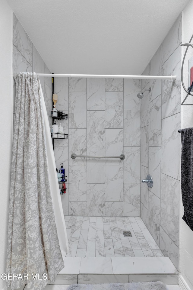 bathroom with marble finish floor and tiled shower