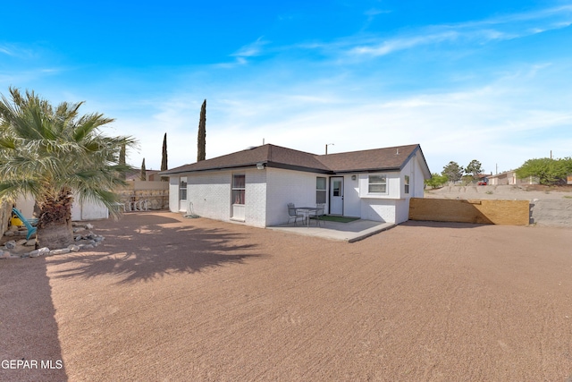 rear view of house featuring brick siding, a patio, and fence