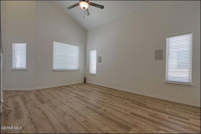 unfurnished room featuring light wood-type flooring, a ceiling fan, high vaulted ceiling, and baseboards