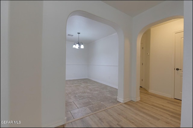 unfurnished room featuring baseboards, visible vents, arched walkways, and a notable chandelier