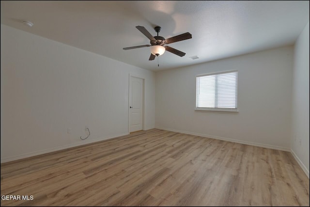 spare room with light wood-style floors, ceiling fan, visible vents, and baseboards