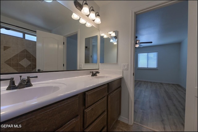full bathroom with double vanity, ceiling fan, baseboards, and a sink