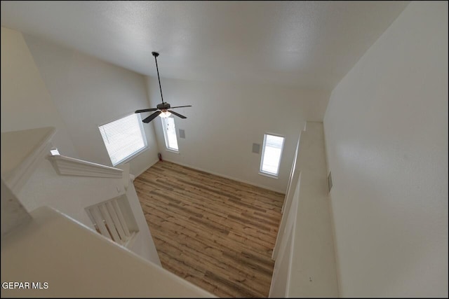 interior space with a ceiling fan, lofted ceiling, wood finished floors, and baseboards