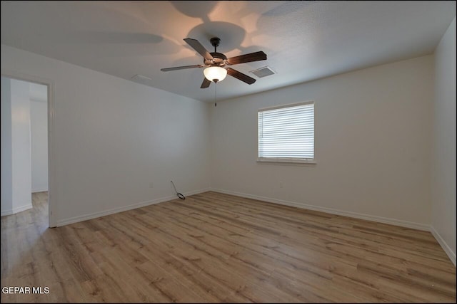 empty room with light wood finished floors, a ceiling fan, visible vents, and baseboards