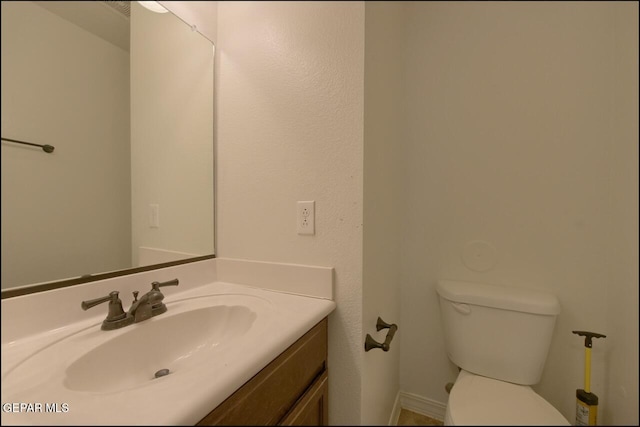 bathroom featuring baseboards, toilet, and vanity