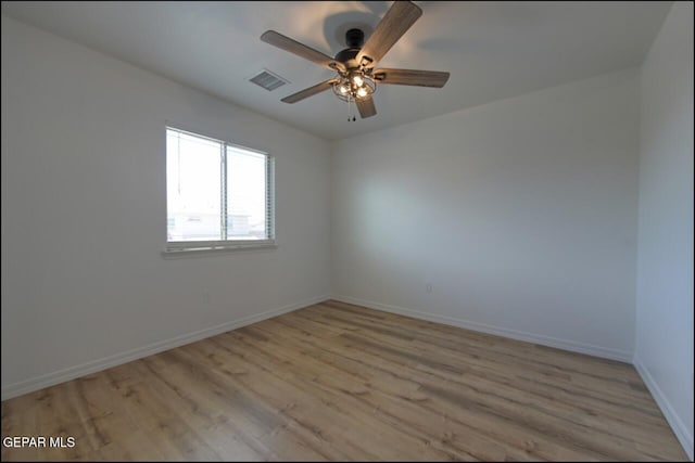empty room featuring baseboards, visible vents, and light wood finished floors