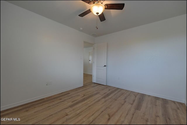 spare room with baseboards, light wood-type flooring, and ceiling fan