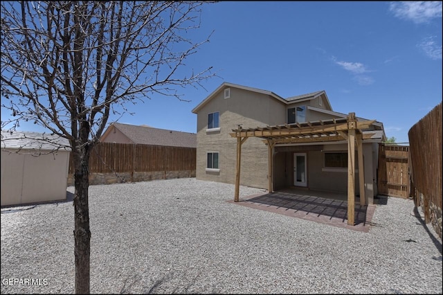 rear view of property featuring stucco siding, a pergola, a patio area, and a fenced backyard
