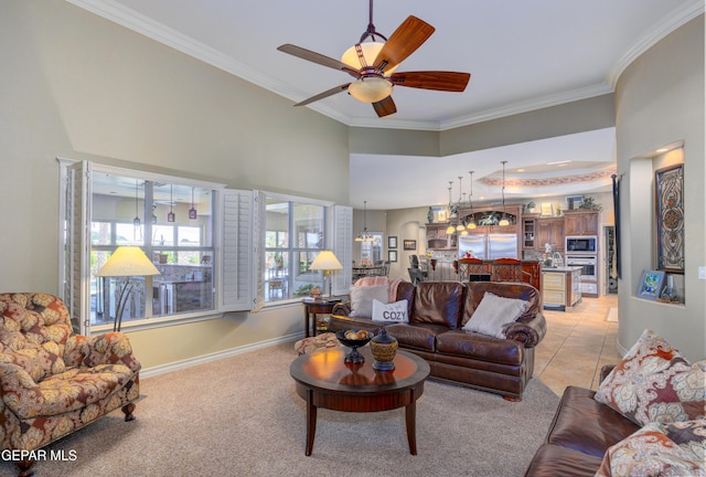 living area featuring crown molding, baseboards, a ceiling fan, and light colored carpet