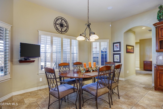 dining space featuring a wealth of natural light, baseboards, and arched walkways