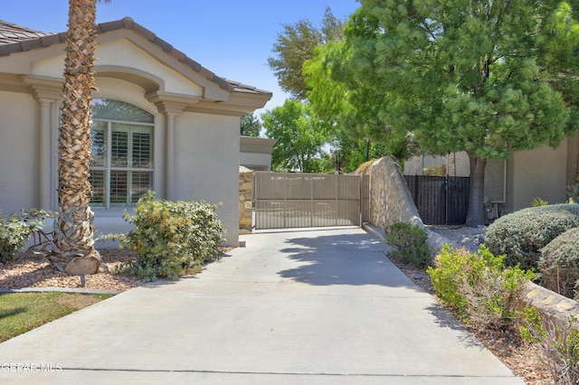 exterior space with a gate, fence, a tiled roof, and stucco siding