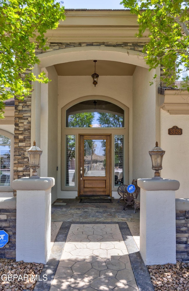 entrance to property featuring stone siding and stucco siding