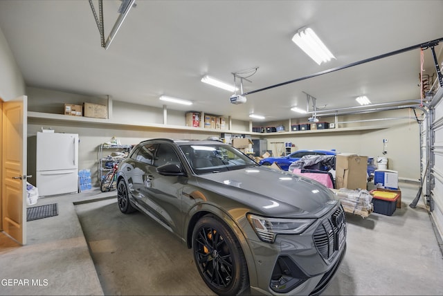 garage with a garage door opener and freestanding refrigerator
