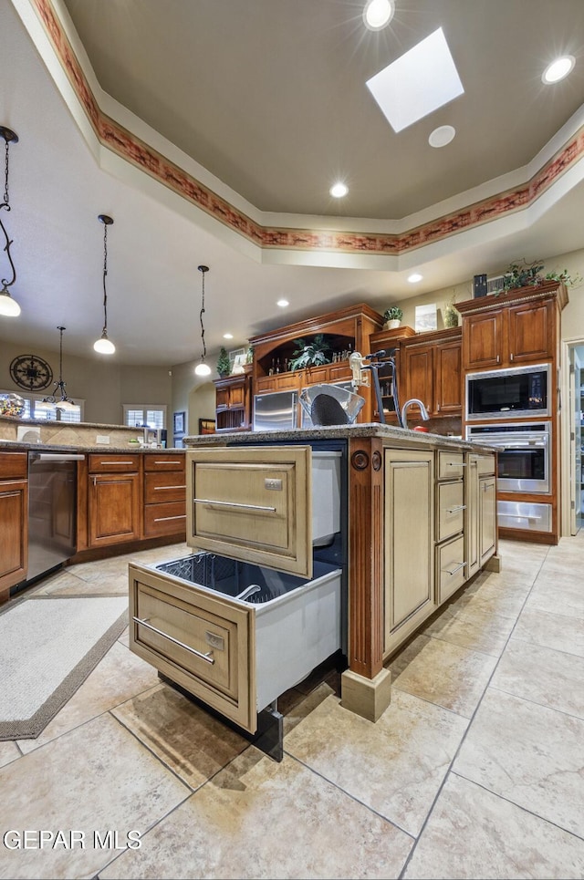 kitchen featuring a skylight, pendant lighting, a raised ceiling, appliances with stainless steel finishes, and recessed lighting