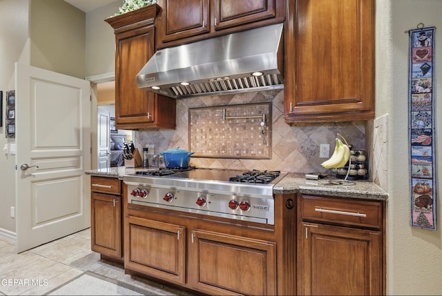 kitchen with stainless steel gas cooktop, backsplash, under cabinet range hood, and light tile patterned floors