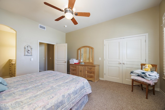 bedroom featuring a closet, arched walkways, light carpet, lofted ceiling, and visible vents