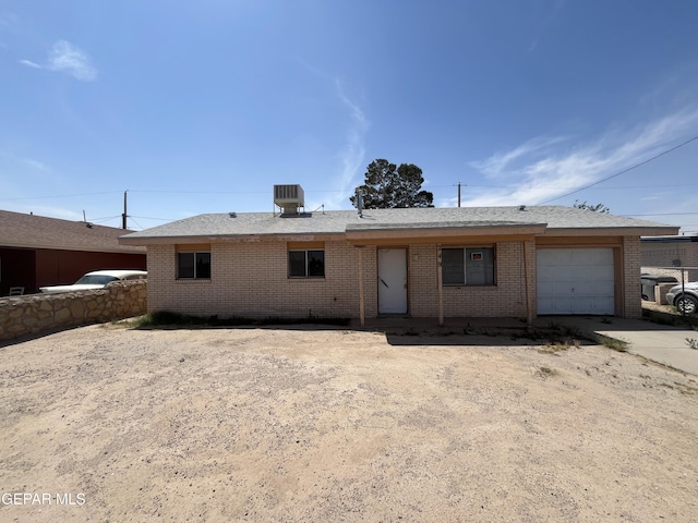 single story home with brick siding, central AC unit, concrete driveway, and a garage