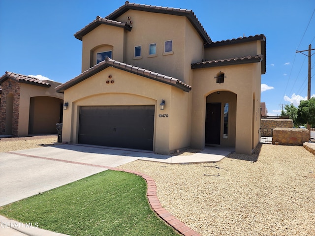 mediterranean / spanish house with a tile roof, stucco siding, driveway, and a garage