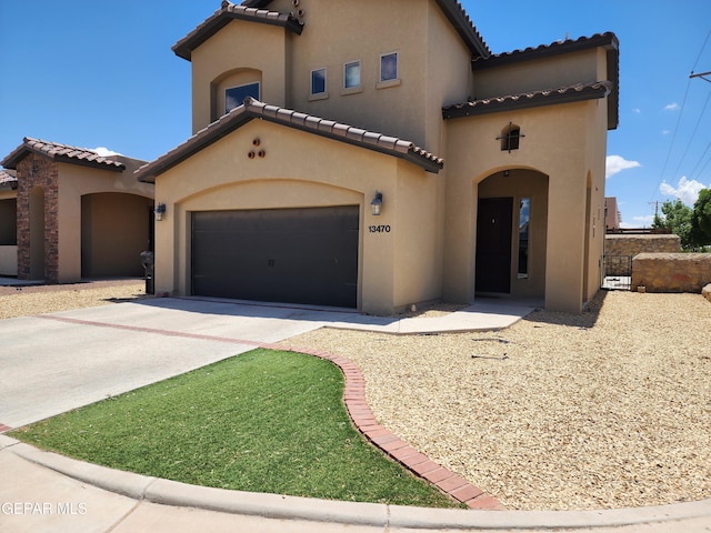 mediterranean / spanish house with a tiled roof, stucco siding, concrete driveway, and a garage