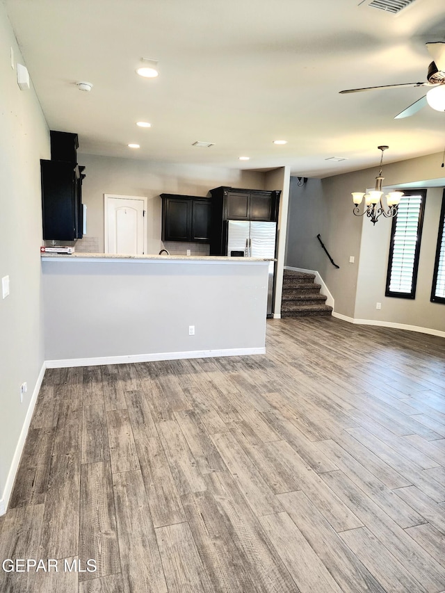 unfurnished living room featuring a ceiling fan, wood finished floors, baseboards, stairs, and recessed lighting