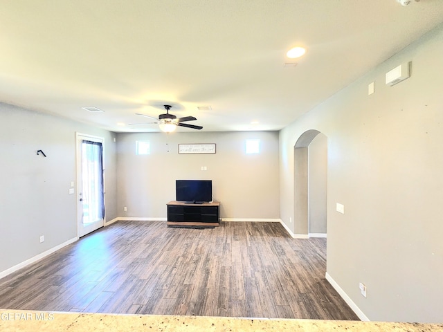 unfurnished living room featuring arched walkways, wood finished floors, and healthy amount of natural light