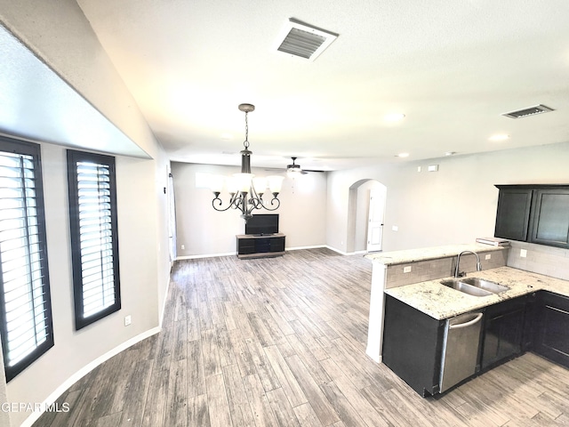 kitchen featuring a sink, light wood-style floors, dark cabinetry, baseboards, and light stone countertops