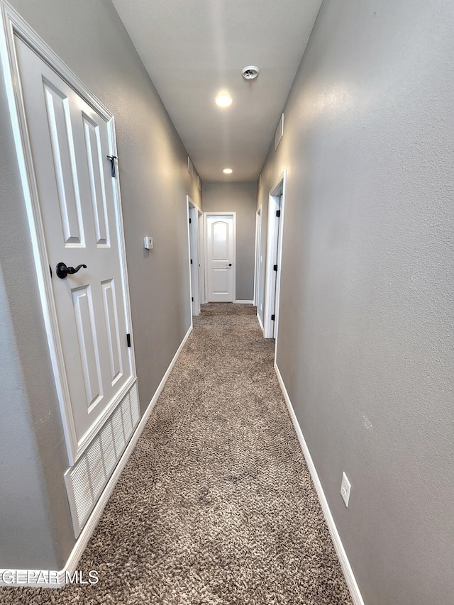 corridor featuring baseboards and carpet