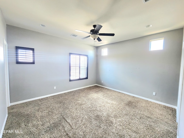 carpeted spare room with plenty of natural light, baseboards, and ceiling fan