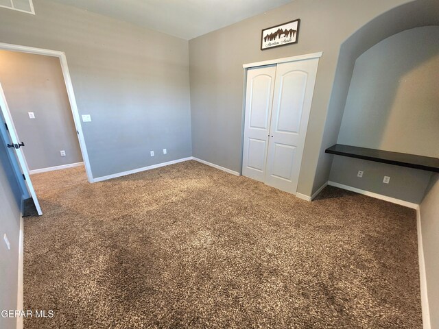 unfurnished bedroom with carpet, a closet, and baseboards