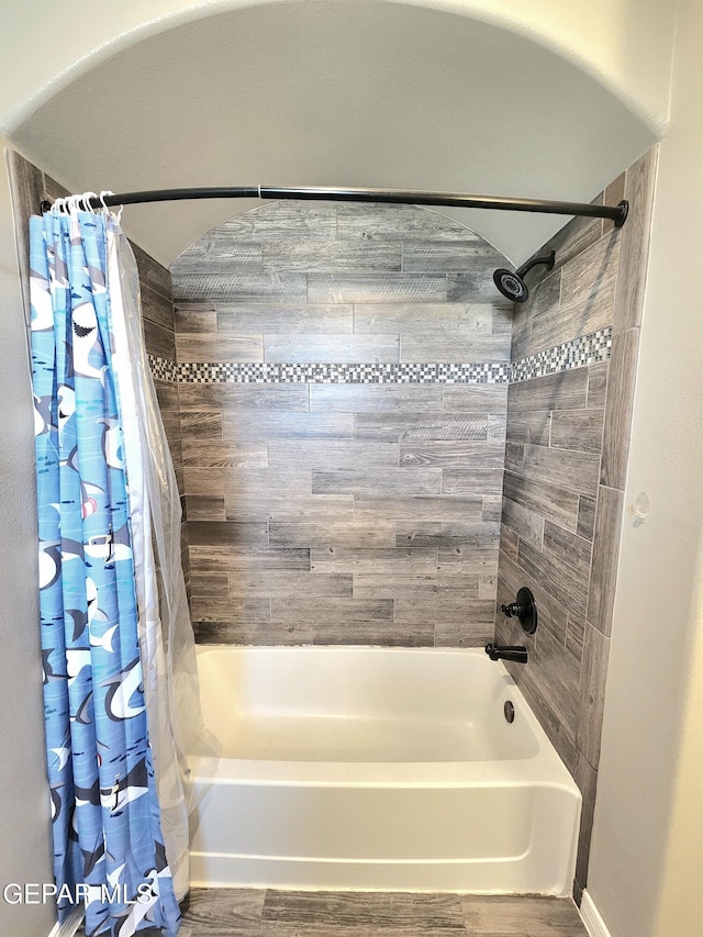 bathroom with shower / bath combination with curtain, wood finished floors, and baseboards
