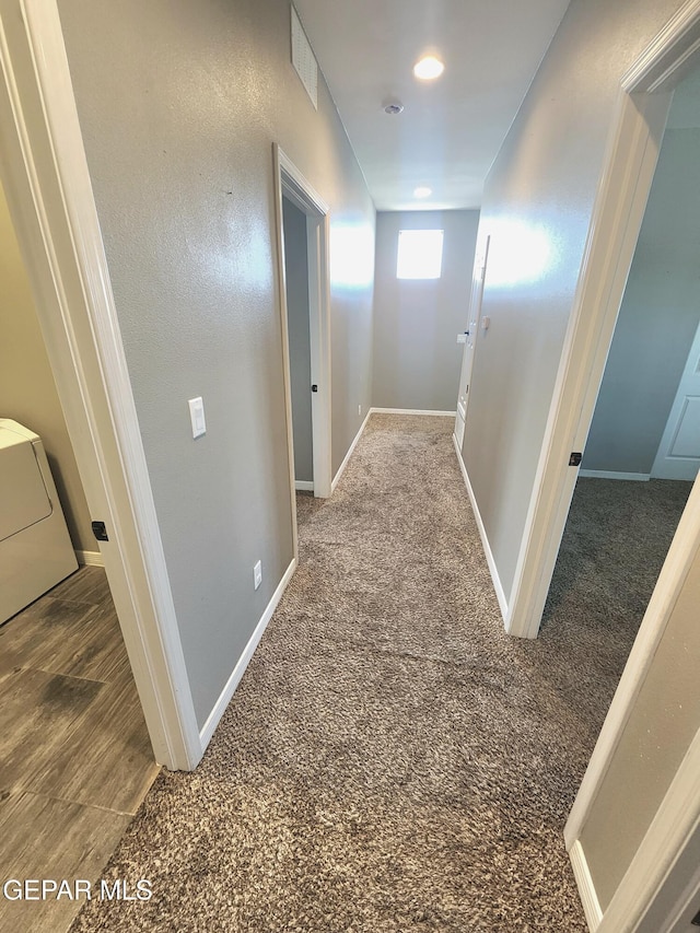 hallway with baseboards, washer / clothes dryer, and carpet flooring