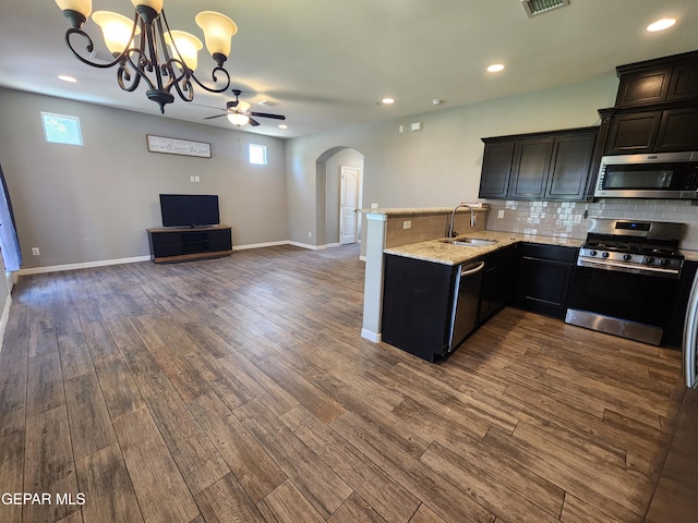 kitchen featuring appliances with stainless steel finishes, a sink, arched walkways, open floor plan, and a chandelier