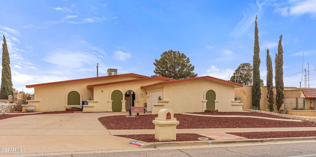 mediterranean / spanish house featuring stucco siding, an attached garage, and driveway