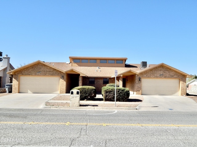 view of front facade with brick siding, central air condition unit, an attached garage, and concrete driveway