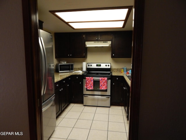 kitchen featuring light stone counters, under cabinet range hood, stainless steel appliances, and light tile patterned floors