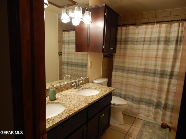 bathroom with double vanity, tile patterned floors, toilet, and a sink