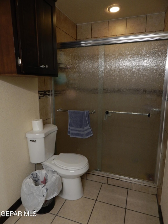 bathroom featuring tile patterned flooring, a shower stall, and toilet