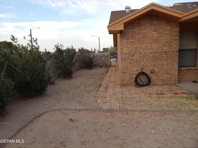 view of side of home with brick siding and fence