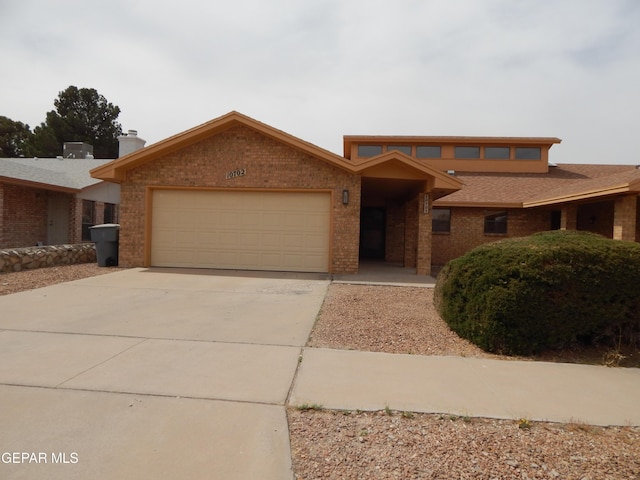 view of front of home with brick siding, an attached garage, roof with shingles, and driveway