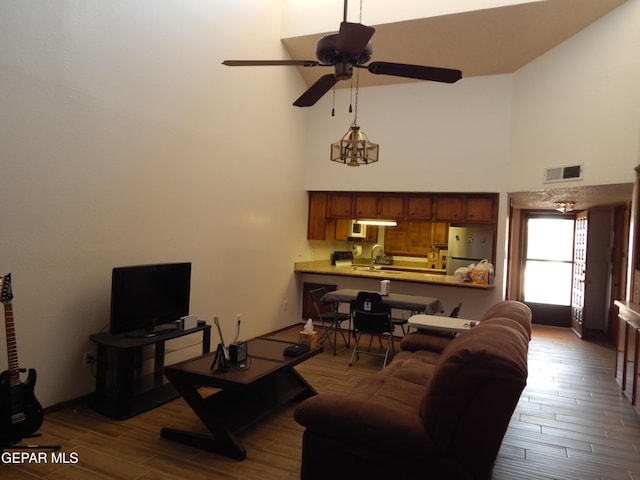 living room with high vaulted ceiling, a ceiling fan, wood finished floors, and visible vents