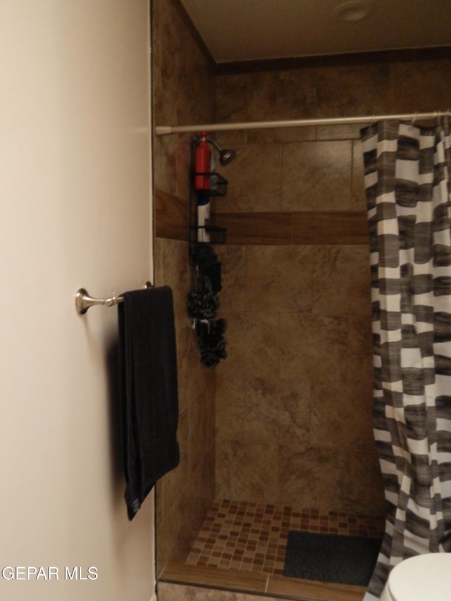 full bath featuring toilet and tiled shower