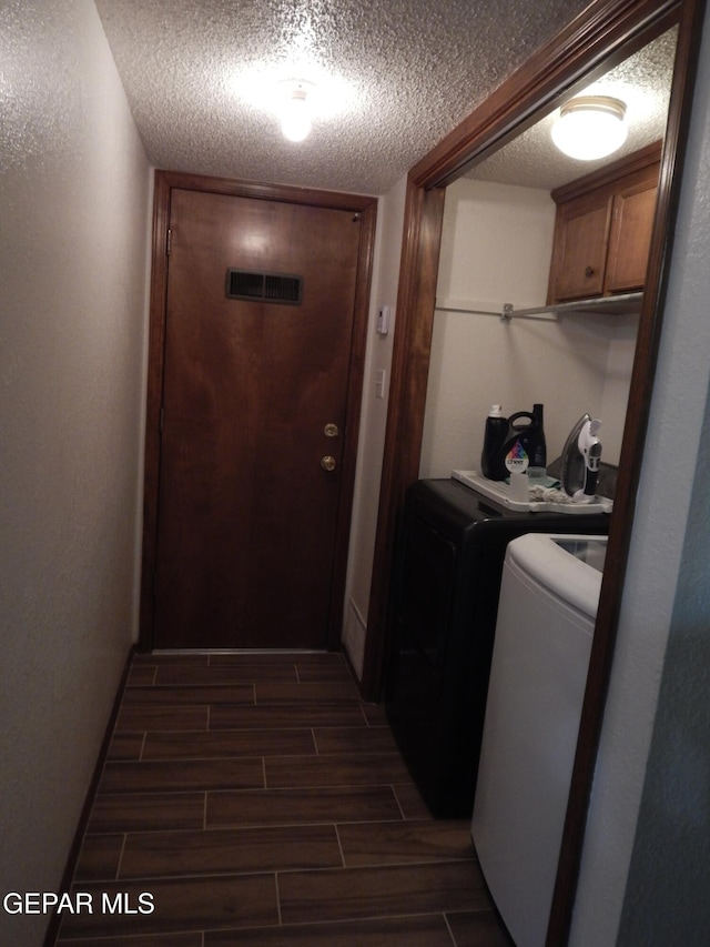laundry room with cabinet space, independent washer and dryer, wood finish floors, and a textured ceiling