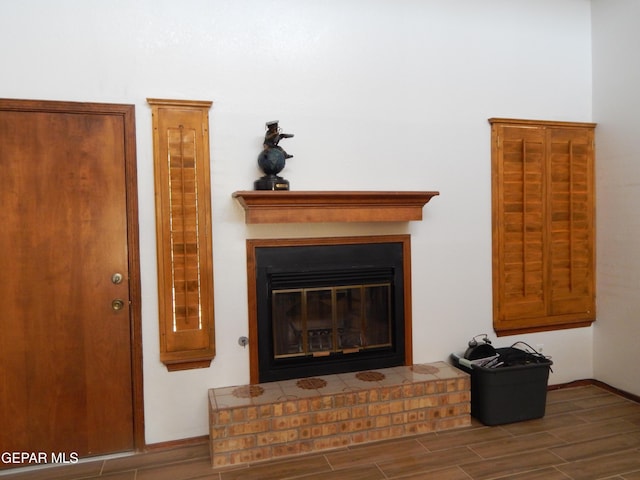 room details featuring a glass covered fireplace, baseboards, and wood finished floors
