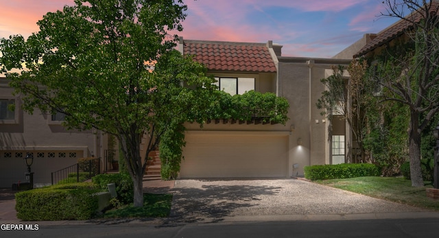 view of front of property with a garage, a tile roof, stucco siding, and aphalt driveway