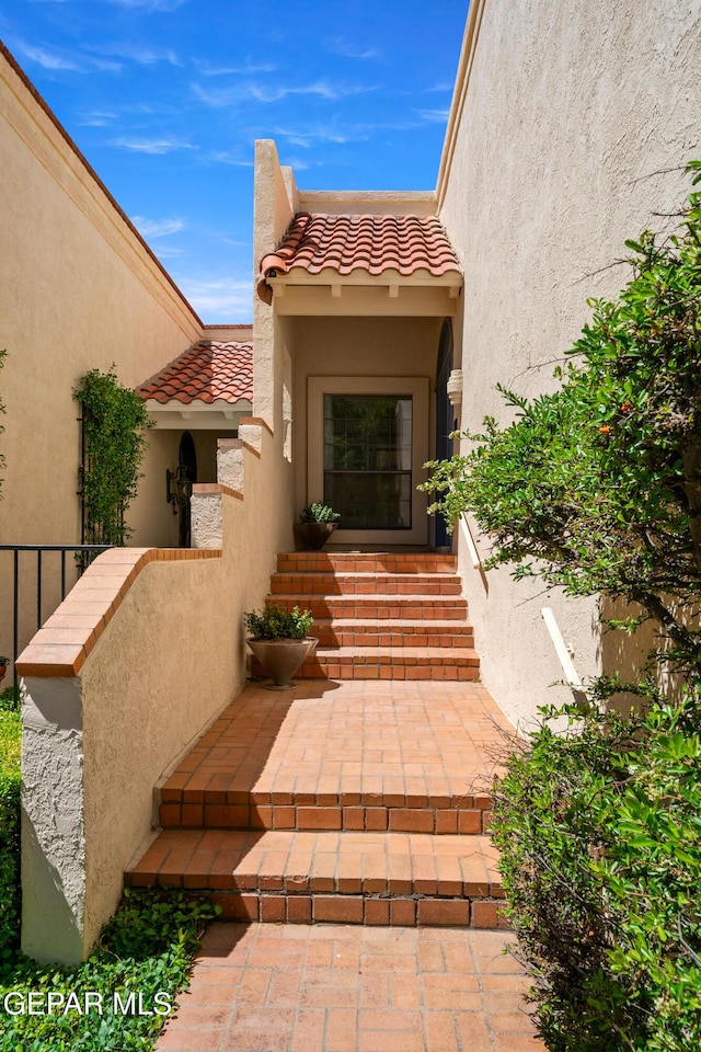 view of exterior entry featuring a tiled roof and stucco siding