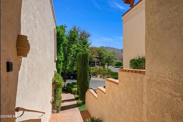 view of property exterior with stucco siding, a mountain view, and a balcony