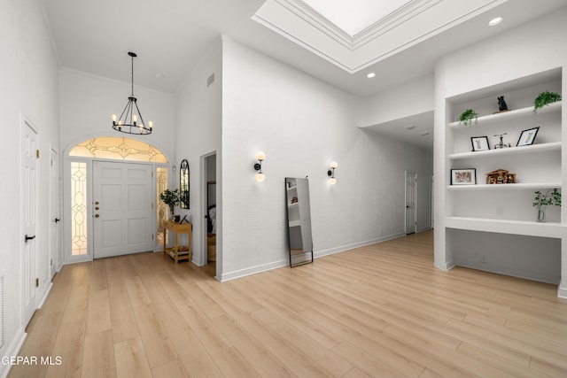 entrance foyer featuring baseboards, a high ceiling, an inviting chandelier, and light wood-style flooring