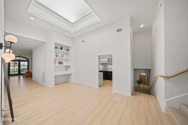 unfurnished living room with recessed lighting, wood finished floors, visible vents, a skylight, and built in features