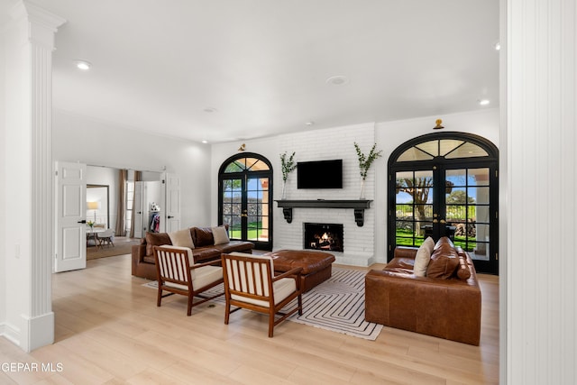 living area featuring french doors, a brick fireplace, recessed lighting, and light wood-style flooring